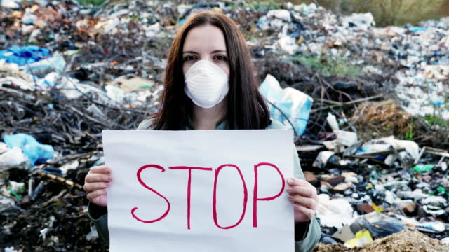 Frau-Aktivist-mit-Stop-Poster-auf-Deponie