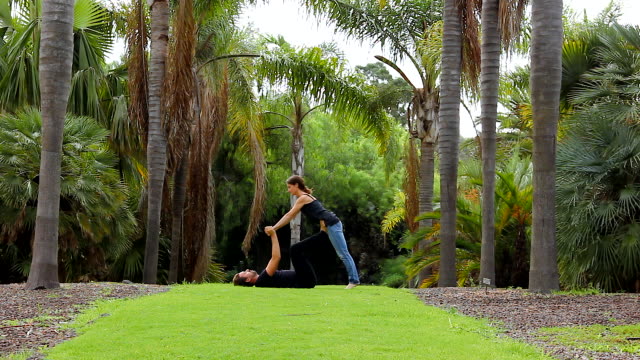 Young-couple-praticing-acro-yoga-in-beautiful-environment-outdoors