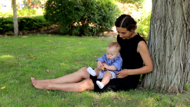 Eine-junge-glückliche-Mutter-geht-mit-ihrem-neugeborenen-Sohn-im-Park-im-Sommer.