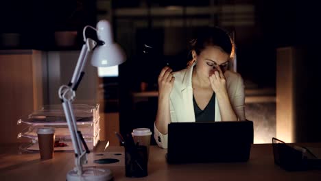 Beautiful-girl-in-formal-clothing-in-working-on-laptop-alone-in-dark-office-late-at-night-finishing-urgent-work-overworking.-Modern-technology-and-job-concept.