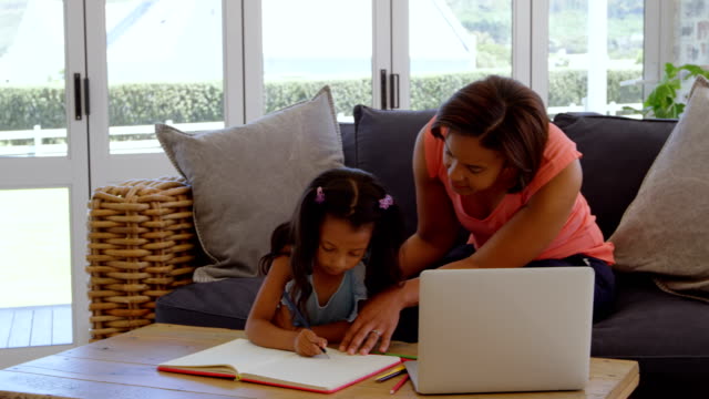 Vorderansicht-der-Reife-schwarze-Mutter-Unterstützung-ihrer-Tochter-bei-den-Hausaufgaben-in-einem-komfortablen-Haus-4k