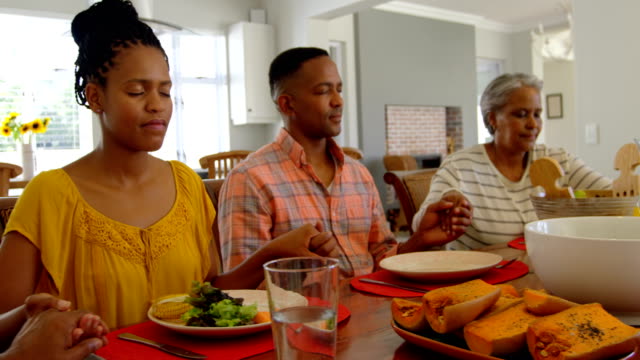 Vorderansicht-der-schwarzen-Familie,-die-betet-zusammen-am-Esstisch-in-komfortablen-Zuhause-4k