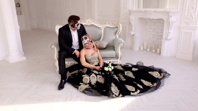 Ehepaar-mit-einem-gruseligen-Halloween-Make-up-sitzen-auf-einem-Vintage-Sofa-in-einem-Vintage-Raum.