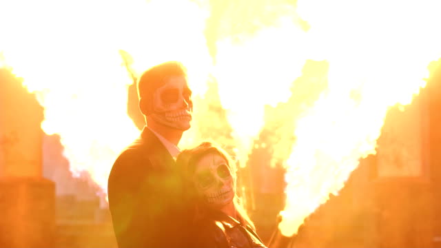 Couple-with-a-terrible-makeup-for-Halloween,-in-the-background-a-huge-flame.