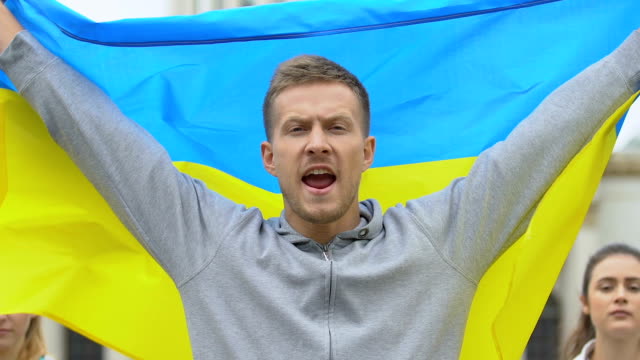 Ukrainian-male-activist-raising-flag,-peaceful-reform-rally,-patriotic-nation