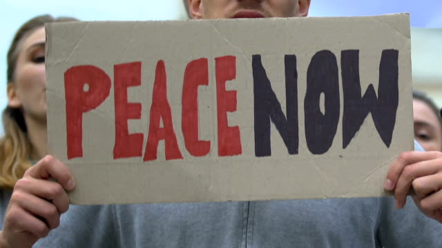 Manifestantes-con-pancartas-gritando-Paz-ahora,-movimiento-anti-guerra,-contra-el-terrorismo