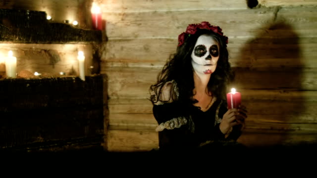Young-woman-with-scary-skeleton-Halloween-make-up-holding-a-lighted-candle.-HD