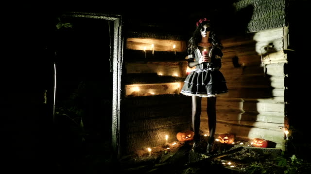 Junge-Frau-mit-beängstigend-Skelett-Halloween-Make-up-hält-eine-beleuchtete-Kerze.-Hd