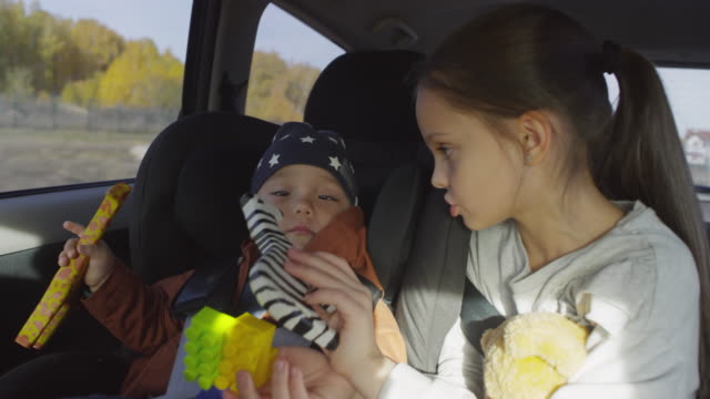 Girl-Playing-with-Toddler-Boy-during-Car-Ride