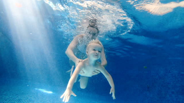 Schwimmbad.-Mama-lehrt-ein-Kind-im-Pool-zu-schwimmen.