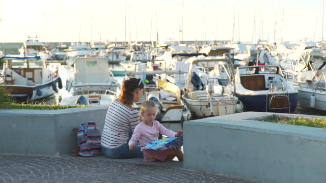 Mutter-und-Tochter-Touristen-in-einem-Hafen-bei-Sonnenuntergang