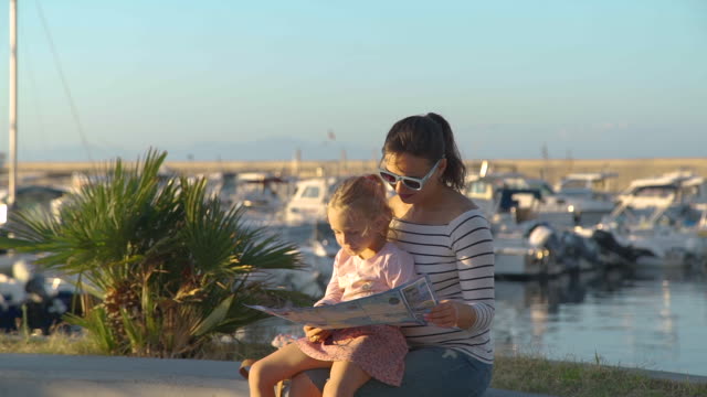 Mujer-joven-con-hija-leyendo-mapa-turístico