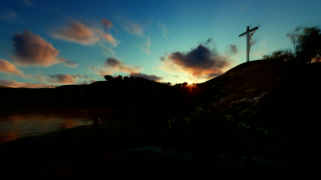 Woman-praying-at-Jesus-cross-against-beautiful-sunset