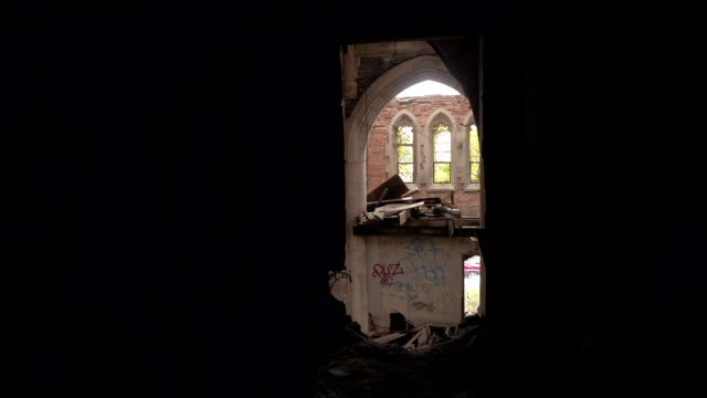POV:-Verfallene-alte-gotische-Kathedrale-gesehen-durch-ein-Loch-in-einer-verfallenen-Mauer
