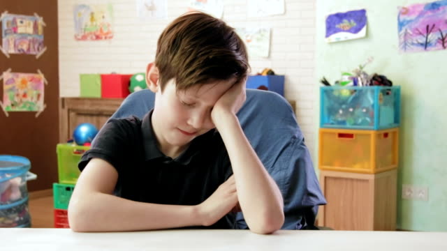 Sad-boy-feeling-sleepy-sitting-at-the-desk-in-his-room