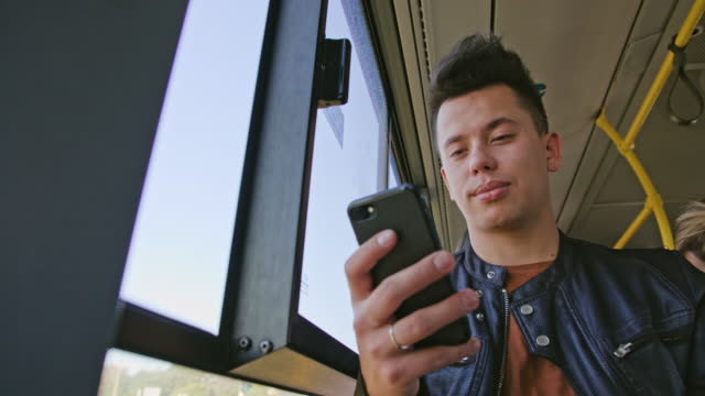 Ein-junger-Mann-mit-einem-Smartphone-auf-dem-Bus