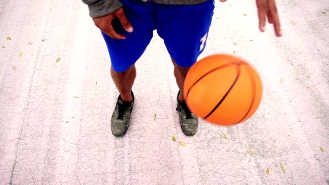 Vista-de-cerca-del-hombre-afroamericano-irreconocible-practicando-baloncesto-fuera.-Vista-desde-la-parte-superior.-Tiro-de-cámara-lenta