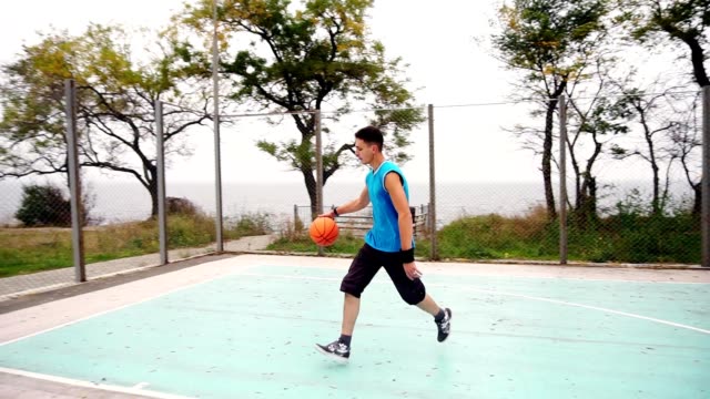 Junger-Mann-wirft-Basketball-Ball-auf-Platz-im-Park-erfolgreich,-Zeitlupe-erschossen