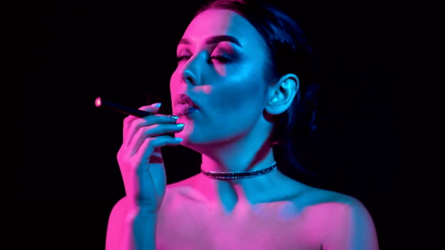 Hermosa-mujer-morena-fumar-cigarrillo-electrónico-en-luz-de-neón-color