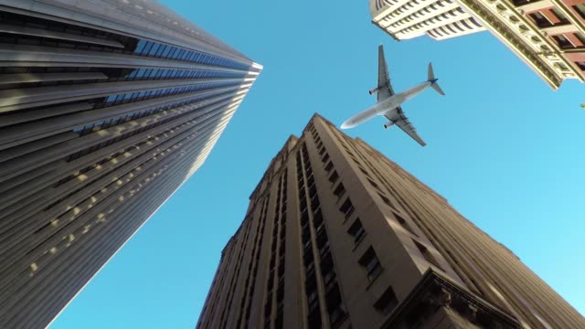 ABAJO-hacia-arriba:-Moderno-aeroplano-sobrevuela-imponentes-rascacielos-en-la-ciudad-metropolitana.