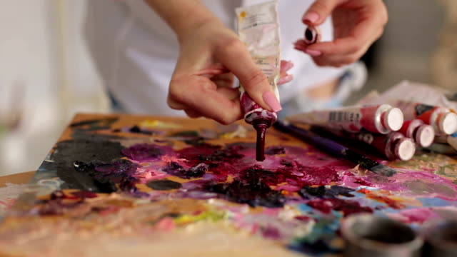 Artist-squeezes-the-paint-from-the-tube-on-palette