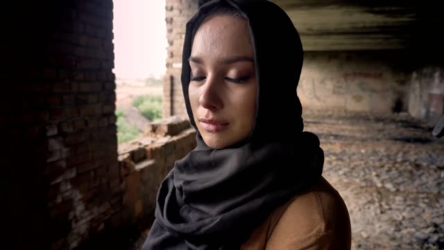 Porträt-des-jungen-traurig-Muslima-Hijab-Weinen,-bewaffnete-Soldaten-zu-Fuß,-verlassenes-gebäude-hintergrund,-militärisches-Konzept