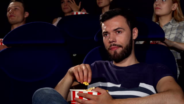 Palomitas-atractivo-joven-comiendo-durante-la-aburrida-película-en-el-cine