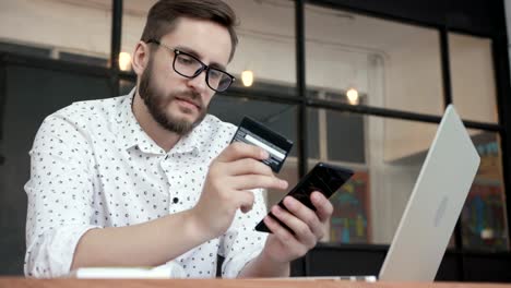 Man-using-online-banking-with-smart-phone-and-card