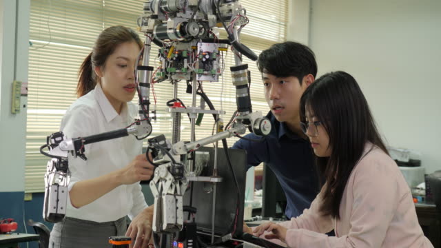 Robotik-Ingenieur-Team-arbeitet-mit-Roboter,-Montage-und-Prüfung-von-Robotik-Antworten-mit-Laptop-Computer-in-Werkstatt.-Menschen-mit-Technologie-oder-Innovation-Konzept.