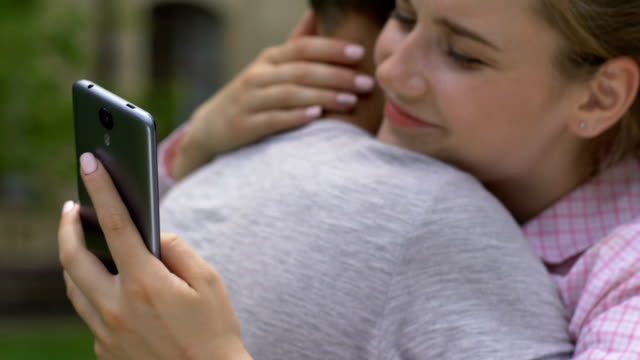 Girl-texting-on-smartphone-while-embracing-boyfriend,-lie-and-betrayal,-closeup