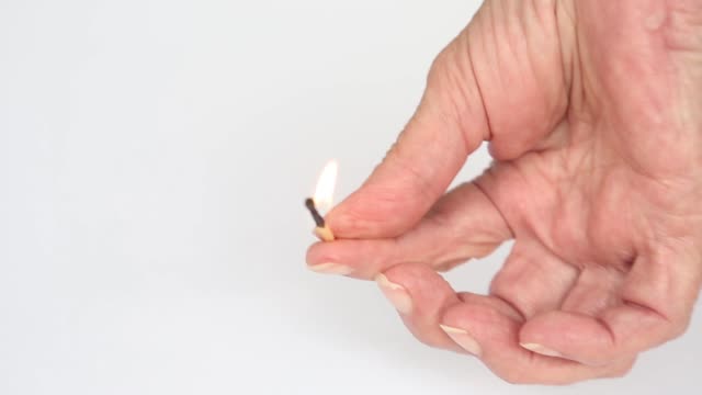 closeup-of-an-older-womans-hand-holding-a-burning-matchstick