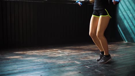 Slow-Motion-junge-ernsthafte-Boxerin-in-umschlossenen-Händen-Aufwärmen,-springen-auf-Springseil-im-Fitness-Studio