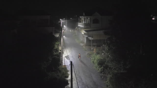 Starke-Regenfälle-in-der-Nacht.-Mann-mit-dem-Motorrad-in-die-kleine-Straße