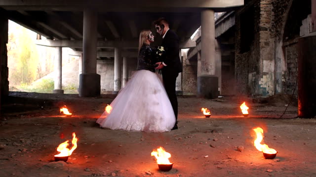 Portrait-of-couple-in-wedding-dresses-for-Halloween,-around-them-the-fire-burns.