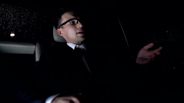 Nervous-businessman-sitting-on-back-seat-of-car,-anxious-about-work,-nighttime