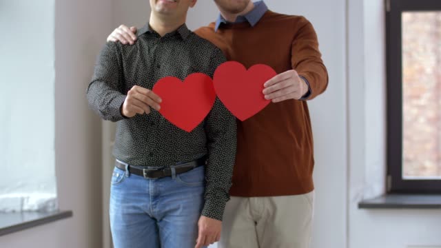 männliche-Homosexuelle-paar-mit-roten-Herzformen-zu-Hause
