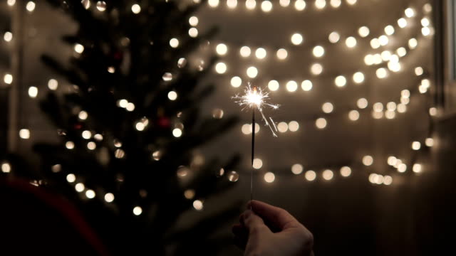 Wunderkerze-in-der-Hand-mit-feiern-Weihnachten-Lichter-Hintergrund