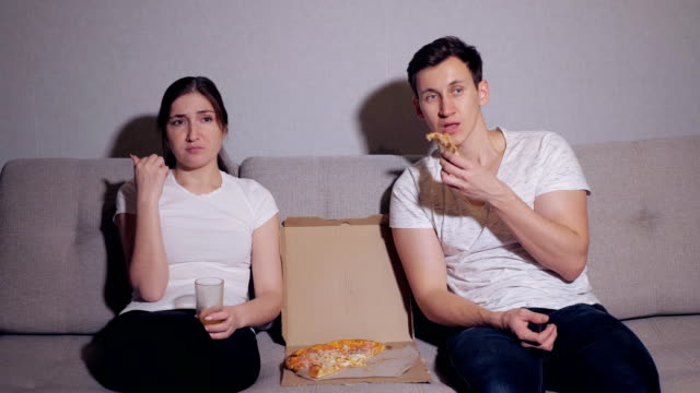 Pareja-feliz-viendo-la-televisión-mientras-comen-pizza