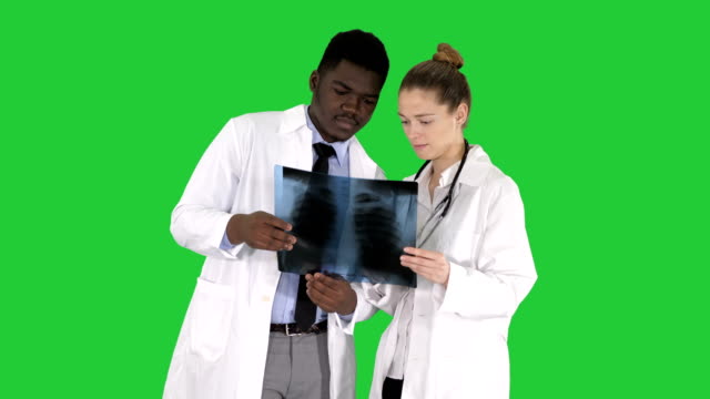 Young-female-doctor-and-afro-american-doctor-looking-at-the-x-ray-picture-of-lungs-on-a-Green-Screen,-Chroma-Key