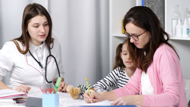 Una-mujer-con-una-hija-joven-hablando-con-un-pediatra-de-médico-en-la-oficina.