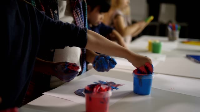 Diverse-Kinder-mit-Händen-in-Farbe-im-Kunstunterricht