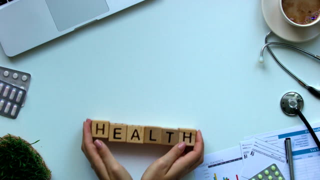 Doctor-pushing-health-word-on-wooden-cubes,-insurance-and-first-aid,-medicine