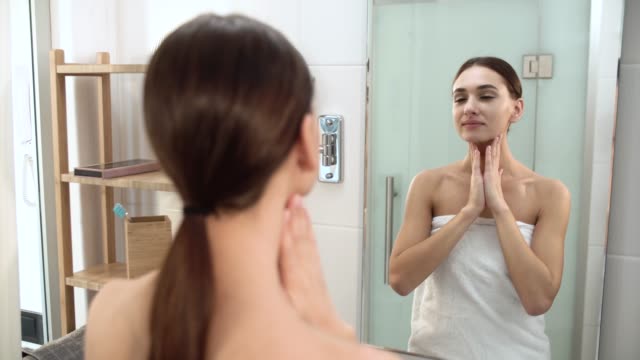 Pflege-der-Haut.-Frau-Gesicht-berühren-und-Blick-auf-den-Spiegel-im-Badezimmer