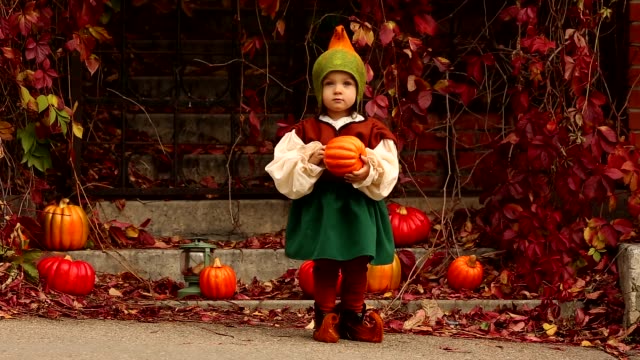 Lustiges-kleines-Mädchen-in-einem-Gnome-Kostüm-hat-einen-Kürbis-in-x-Hand-und-sieht