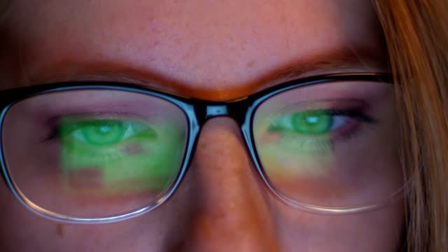 Ziemlich-schöne-Augen-in-der-Nähe-Caucasian-Hacker-Mädchen-schaut-auf-Bildschirm-mit-Informationen-und-es-spiegelt-sich-wie-Bilder-in-ihrer-Brille