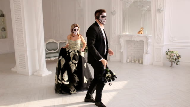 Couple-in-costumes-and-makeup-for-Halloween,-they-dance-in-a-bright-white-room