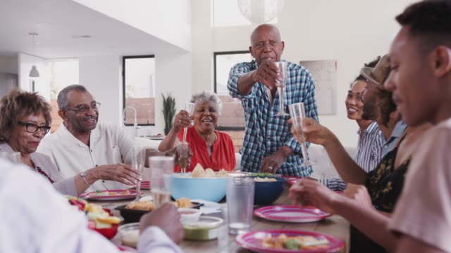 Großvater-steht-am-Esstisch-und-schlägt-einen-Toast-während-einer-Familienfeier,-hautnah