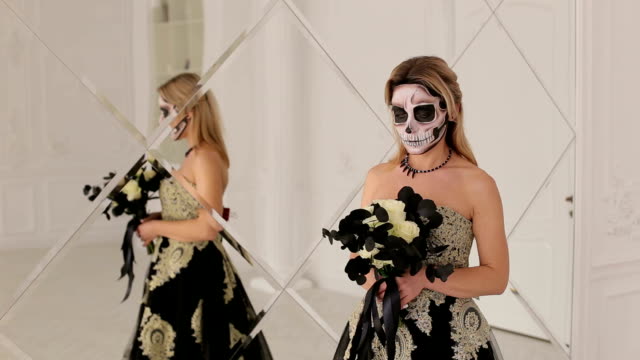 Mädchen-mit-schwarzen-Blumen-und-Make-up-für-Halloween-stehen-in-der-Nähe-von-Spiegel.