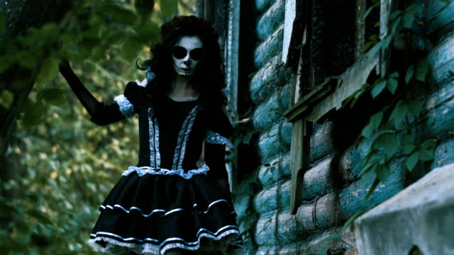 Skeleton-make-up-for-Halloween.-The-young-woman-going-along-the-wooden-house.-4K