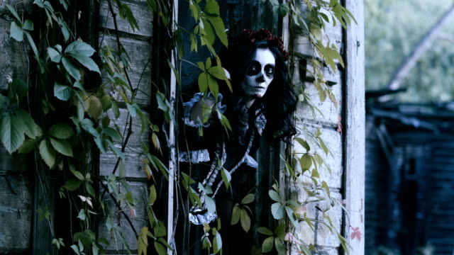 A-young-woman-with-spooky-skeleton-Halloween-make-up-looking-out-the-window.-4K